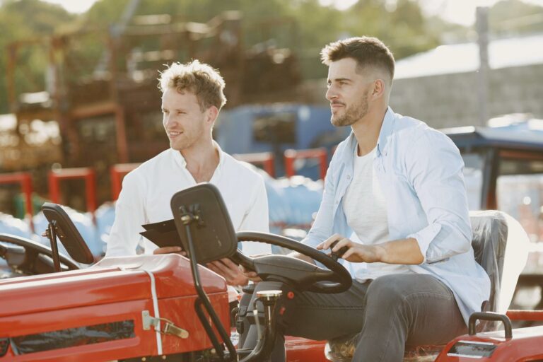 Two men discussing sales while inspecting a tractor outdoors. Ideal for business and agriculture themes.